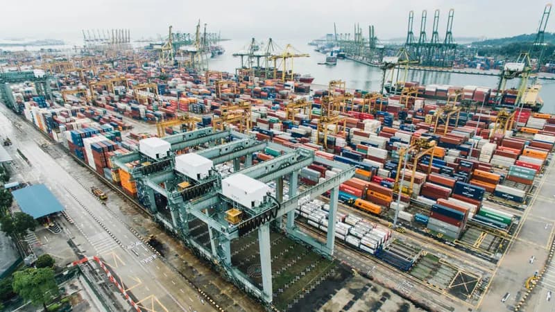 Un terminal à conteneurs vu du ciel : portiques et piles de conteneurs le long du quai.