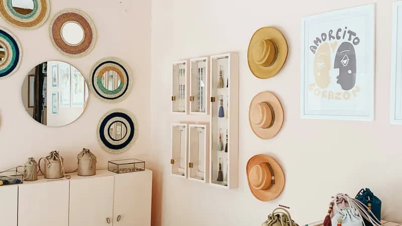 L’intérieur d’une boutique : chapeaux et sacs accrochés au mur, articles disposés sous une vitrine.