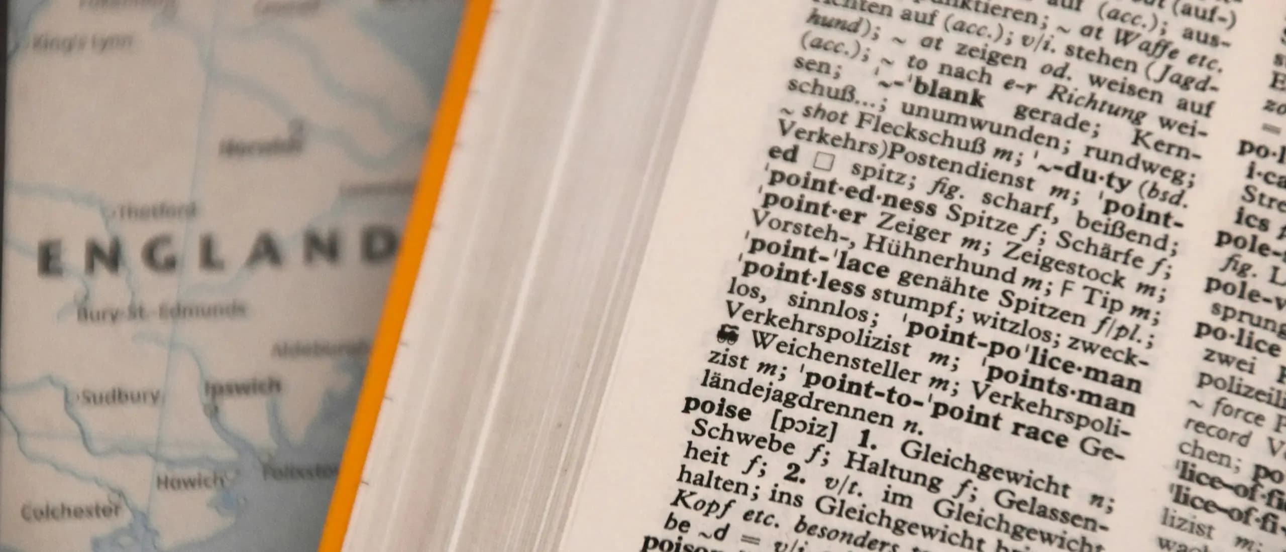 Un dictionnaire bilingue ouvert, posé sur une carte géographique.