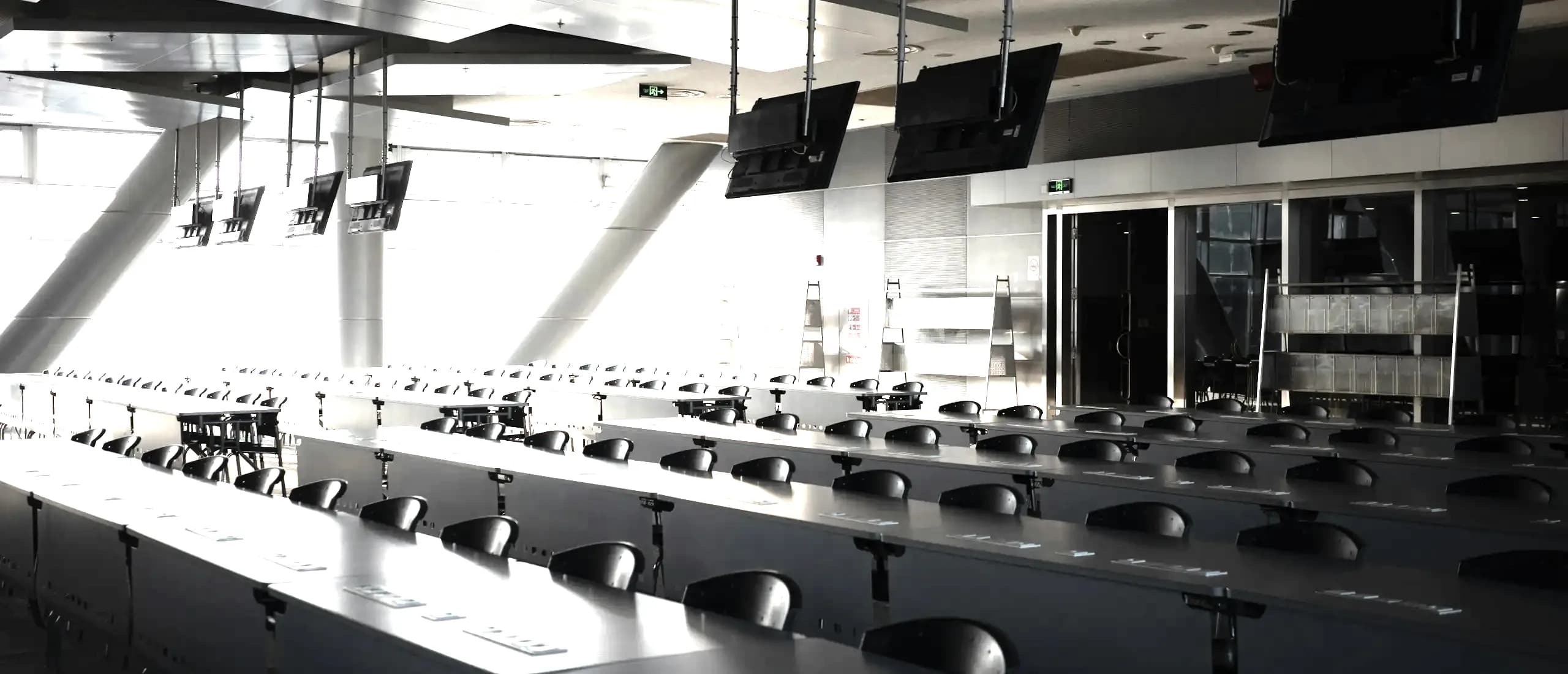 Des rangées de pupitres équipés de postes individuels dans une salle d’examen vide.